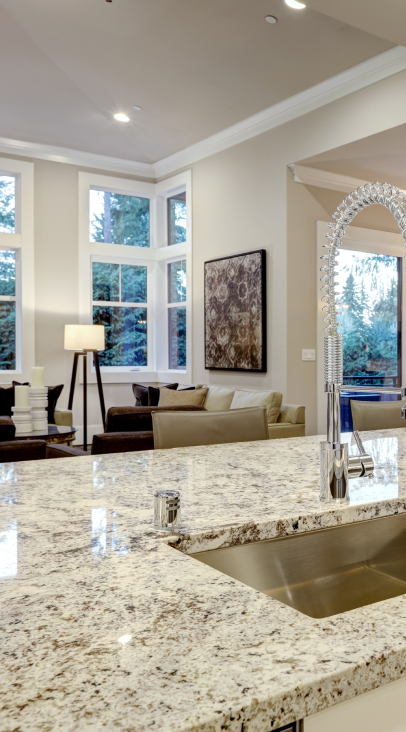 Minimalistic, white living room viewed from atop a beautiful granite kitchen countertop.